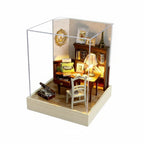 Miniature model of a study room with furniture and decor, enclosed in a glass case with dimensions indicated.