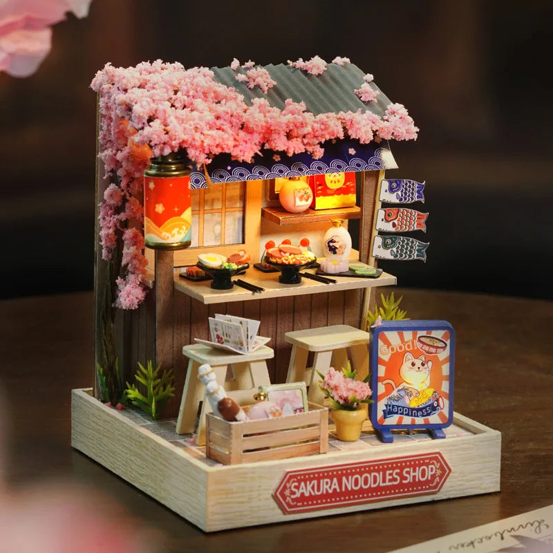 Miniature Sakura Noodles Shop model with cherry blossom decorations on a dark background