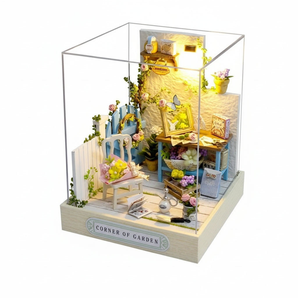 Model of a garden corner with furniture and plants, illuminated inside a clear box.
