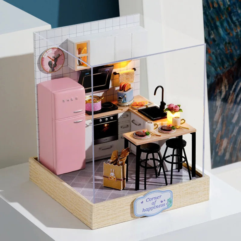 Miniature model of a kitchen with pink refrigerator and dining area.