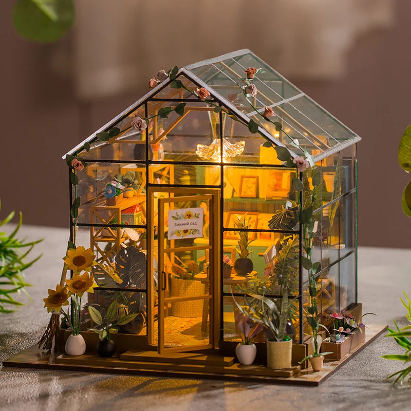 Miniature model of a glass greenhouse with plants inside, glowing warmly.