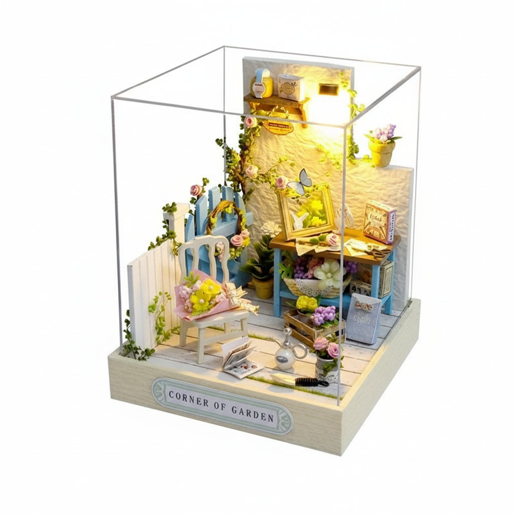 Model of a garden corner with furniture and plants, illuminated inside a clear box.