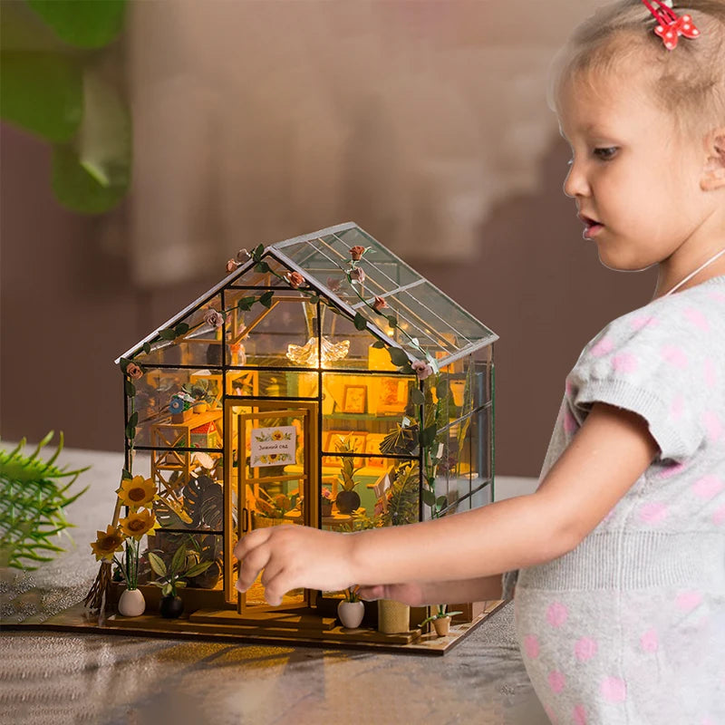 Child playing with a miniature glass greenhouse model