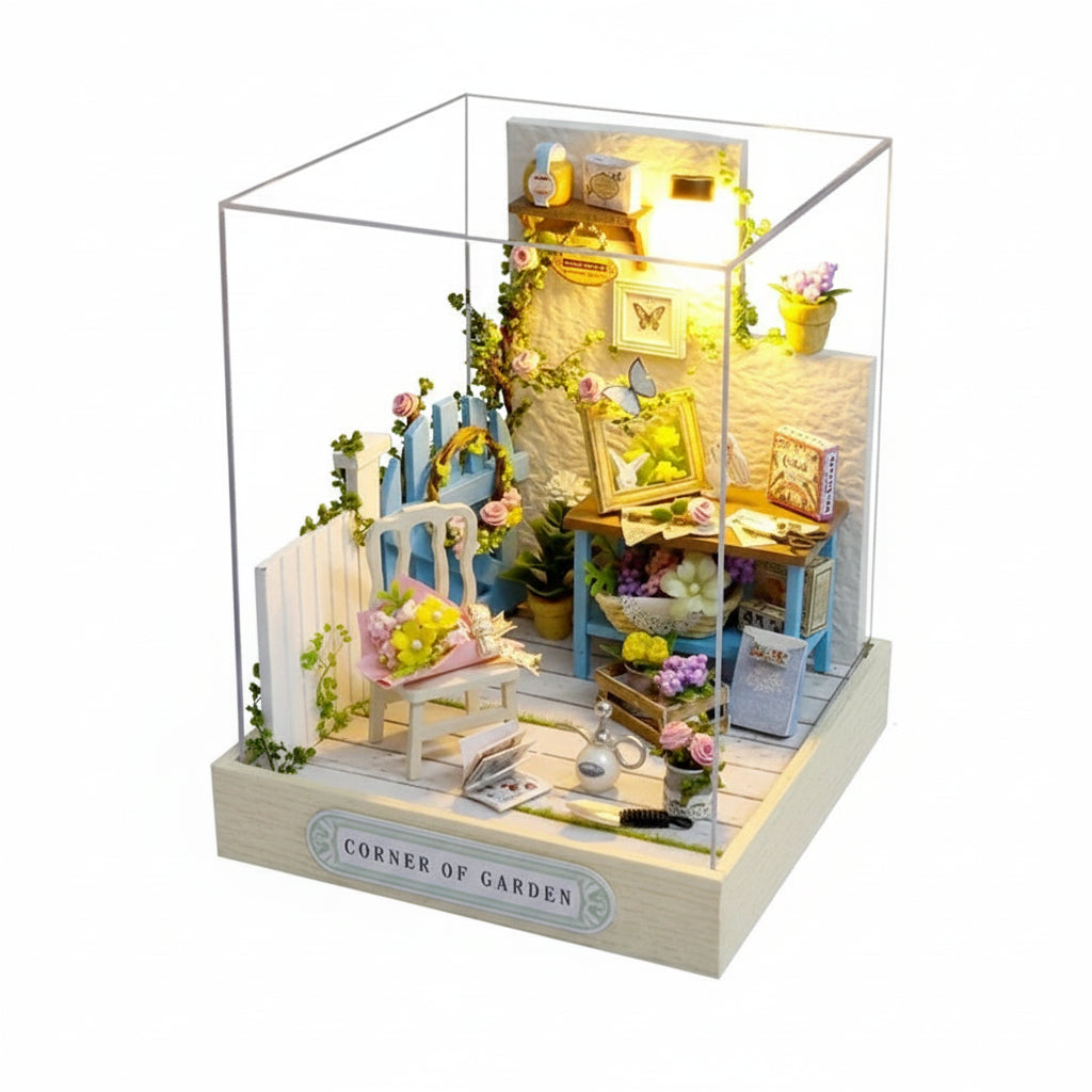 Model of a garden corner with furniture and plants, illuminated inside a clear box.