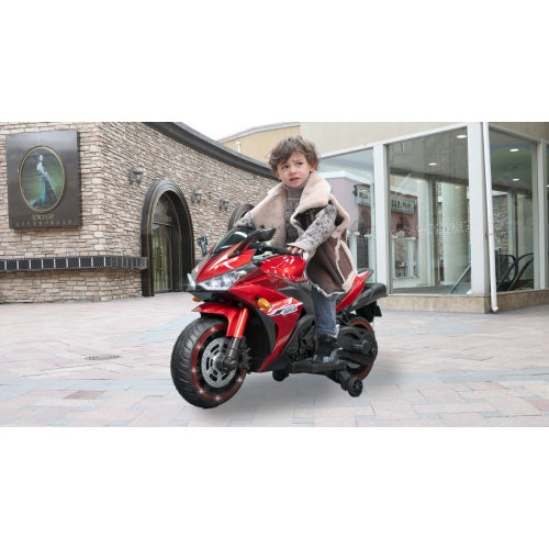 Child riding a red toy motorcycle in front of a building.