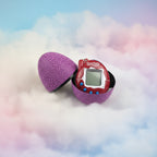 Red and purple Tamagotchi-style toy in a cracked egg-shaped case on a white background