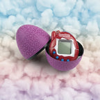 Red and purple Tamagotchi-style toy in a cracked egg-shaped case on a white background