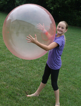Child playing with a large inflatable bubble ball outdoors on grass