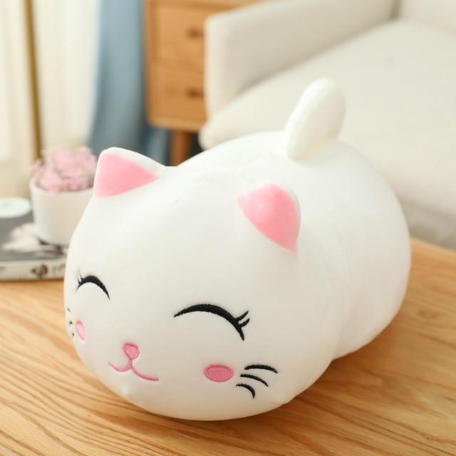 Cute white cat-shaped plush toy on a wooden surface with a blurred background