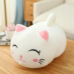 Cute white cat-shaped plush toy on a wooden surface with a blurred background