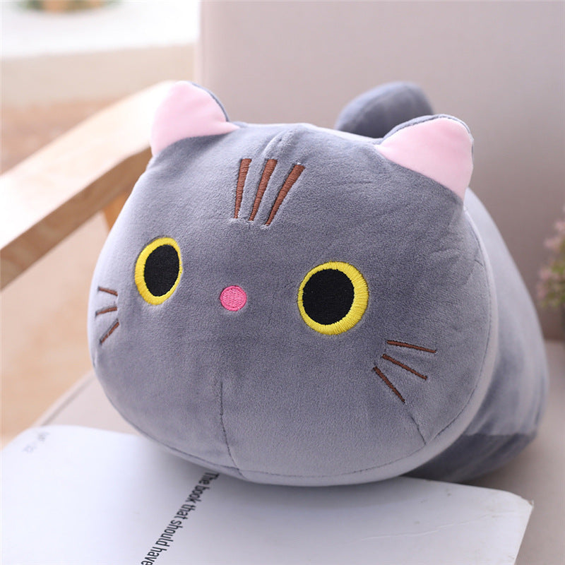 Plush cat-shaped pillow on a surface with a blurred background
