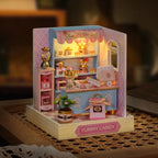Miniature candy shop model with lights on a checkered surface