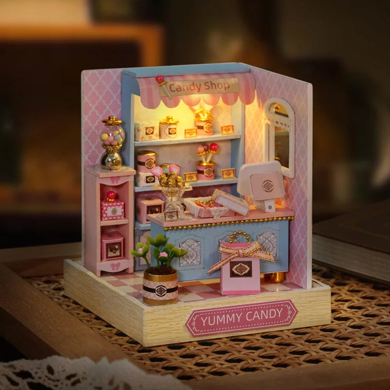 Miniature candy shop model with lights on a checkered surface
