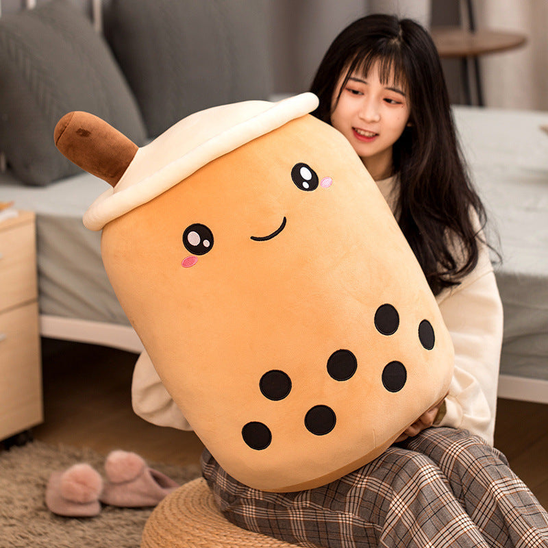 Person holding a plush toy shaped like a bubble tea cup with a smiling face.