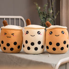 Three plush toys shaped like bubble tea cups with faces on a table.
