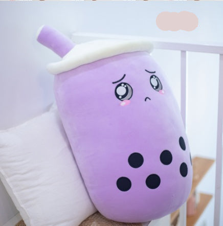 Purple plush toy with black dots and a white top, resembling a bubble tea cup, on a light blue background.