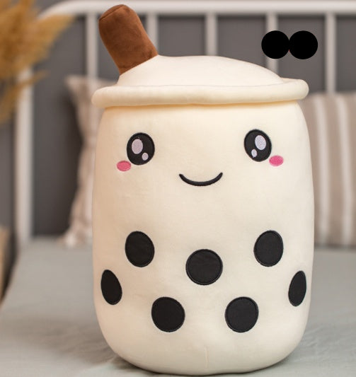 Plush toy resembling a bubble tea cup with a happy face on a soft surface.