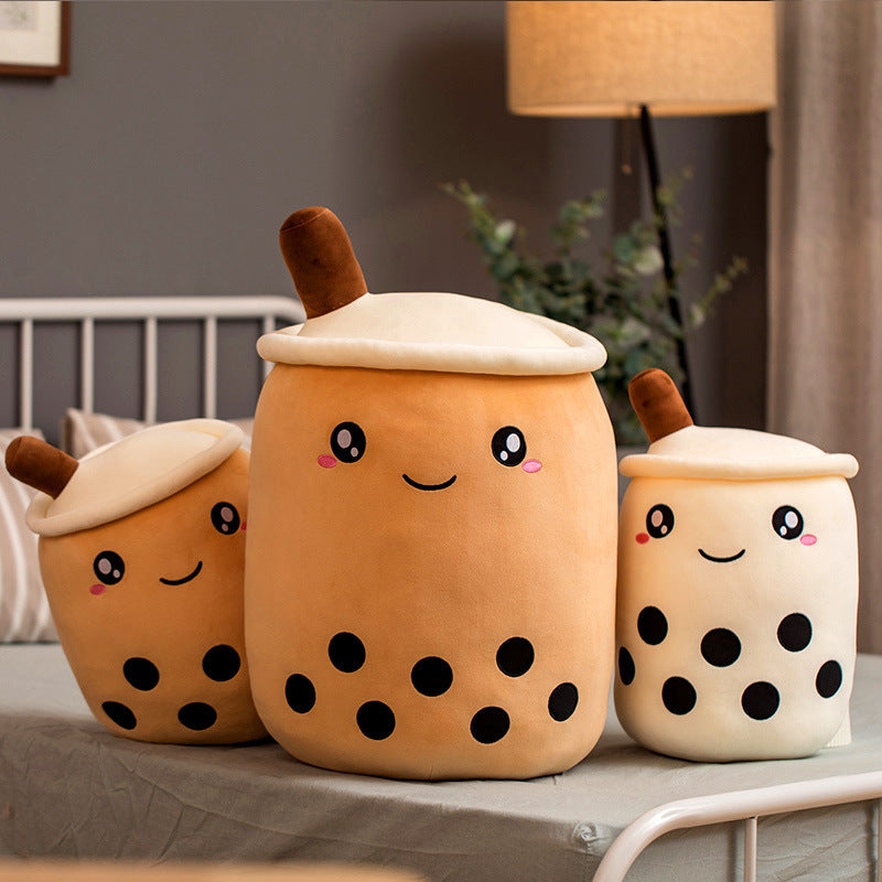 Three plush toys shaped like bubble tea cups on a surface with a neutral background.