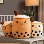 Three plush toys shaped like bubble tea cups on a surface with a neutral background.