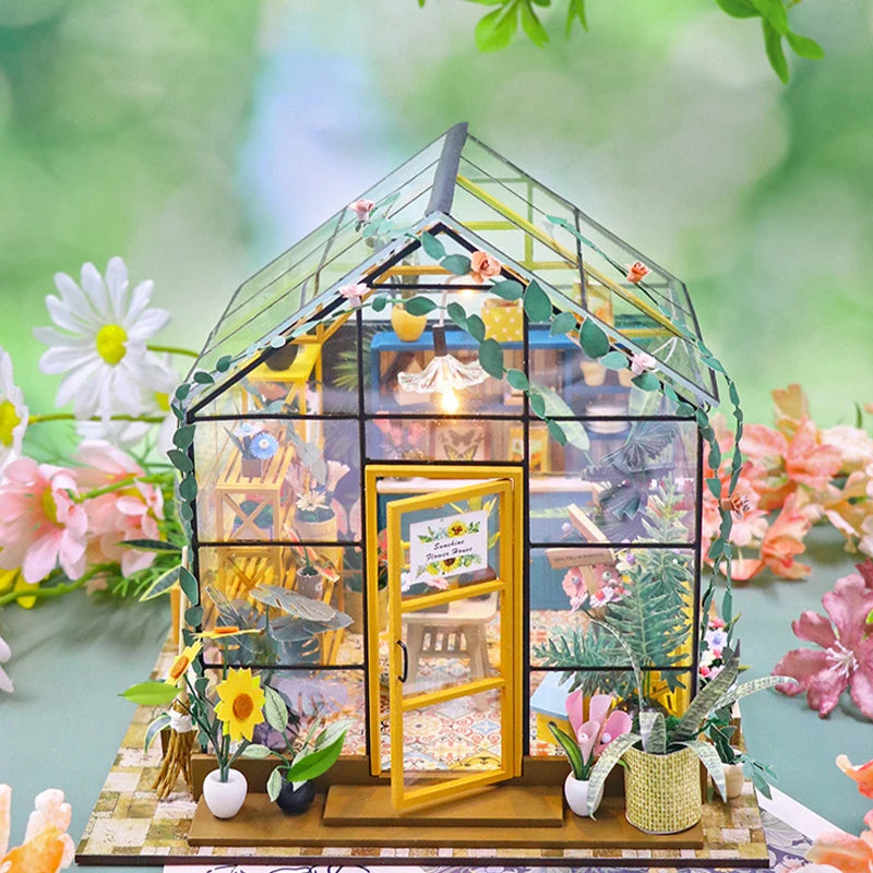 Miniature model of a greenhouse with plants and flowers on a blurred natural background