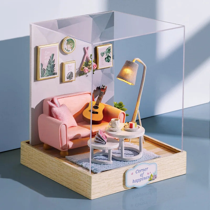 Miniature dollhouse living room set in a clear display case with a pink sofa, guitar, and lamp.