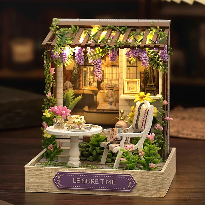 Miniature garden scene with a chair, table, and decorative elements on a wooden base.